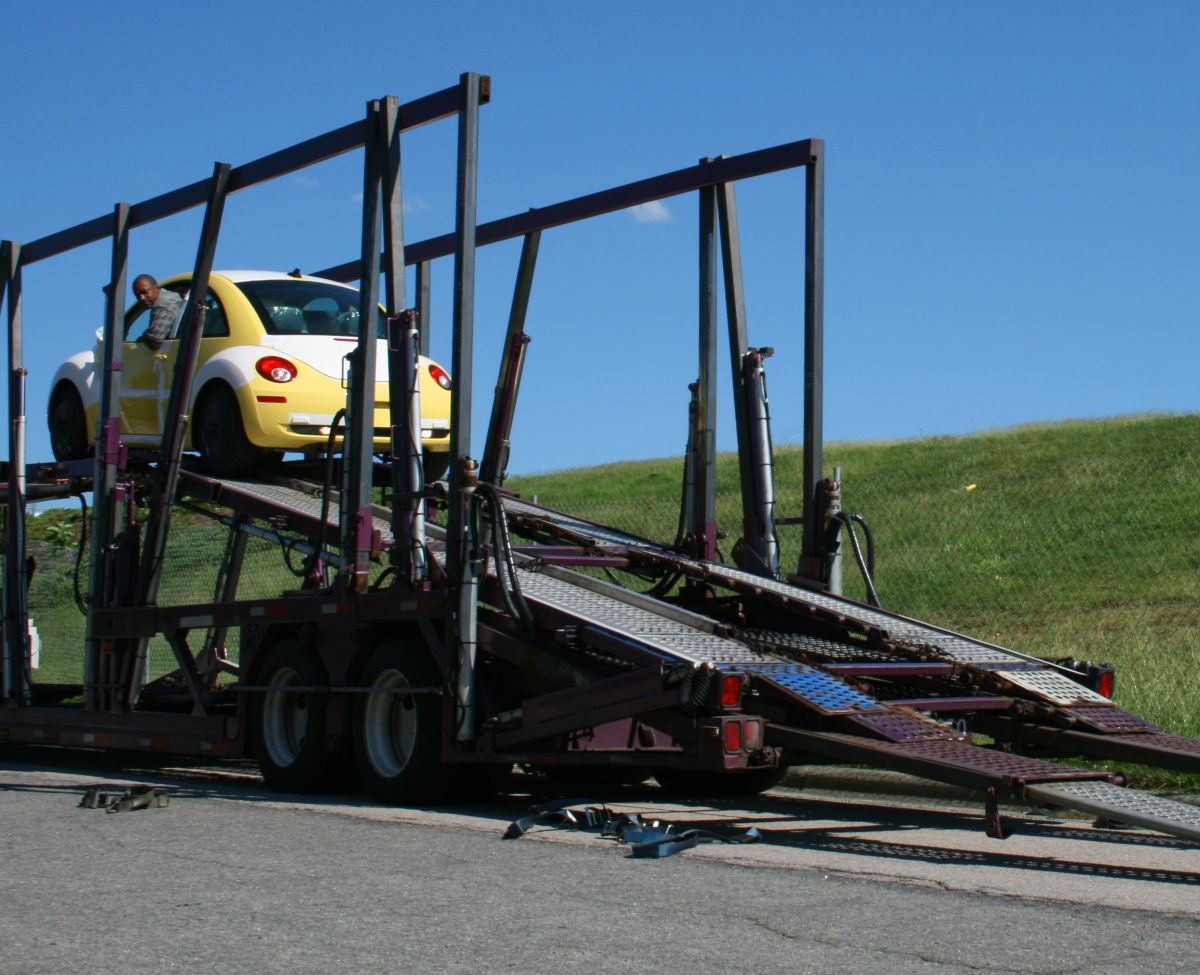 Driver backing a new car down the ramp of a car carrier trailer on delivery in Durham, North Carolina